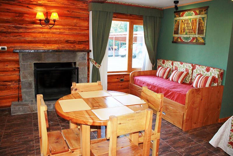 Living del apart familiar con hogar a leña y mesa de madera
