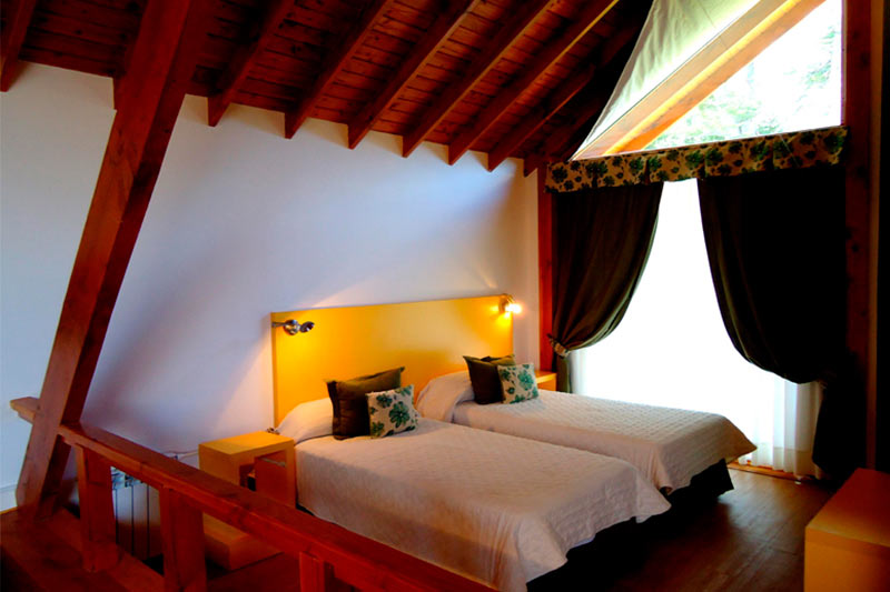 Camas simples bajo el techo de madera del loft