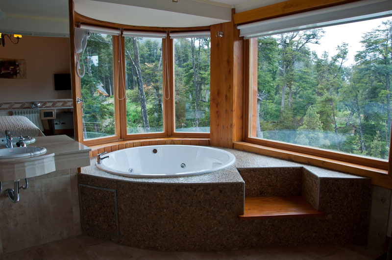 Jacuzzi junto al ventanal con vista al bosque