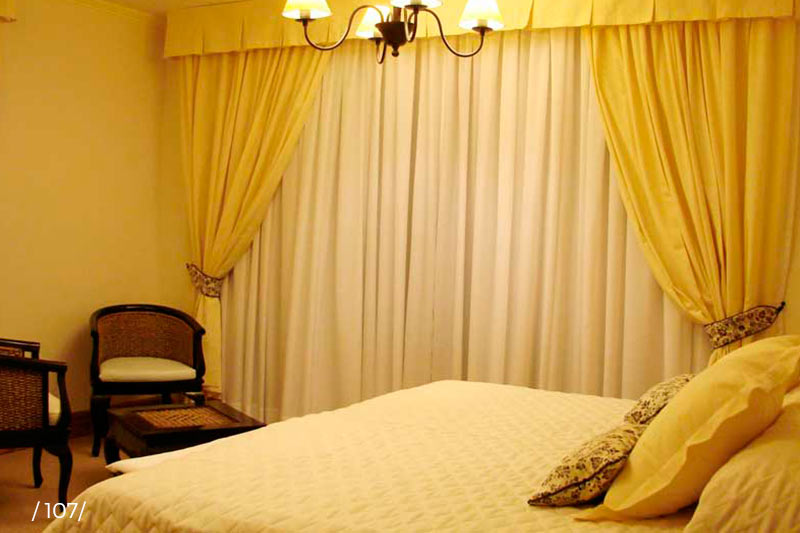 Habitación superior con cortinas amarillas y sillones